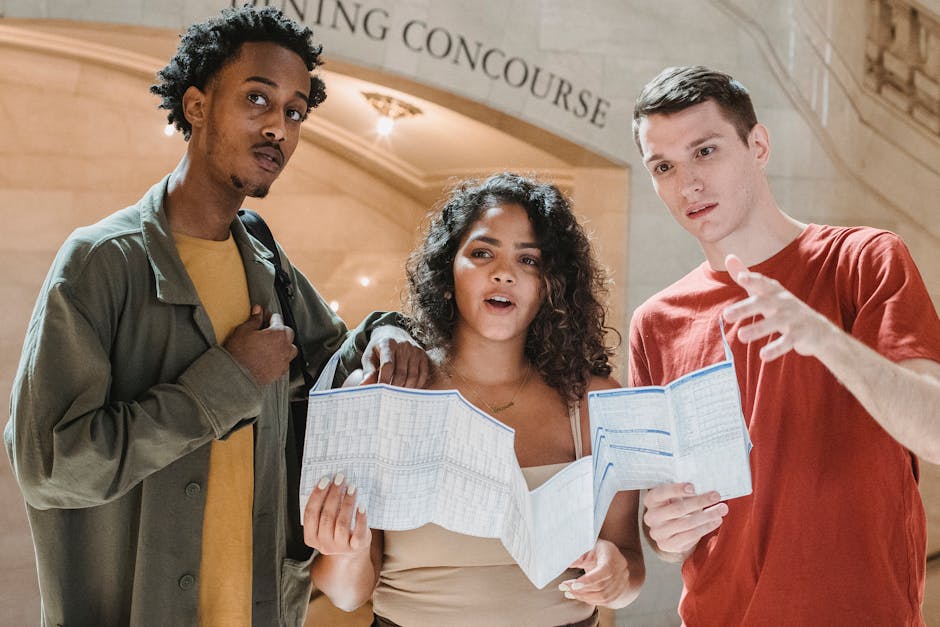 Amazed young multiracial male and female friends in casual outfits looking away while exploring map in Grand Central Terminal